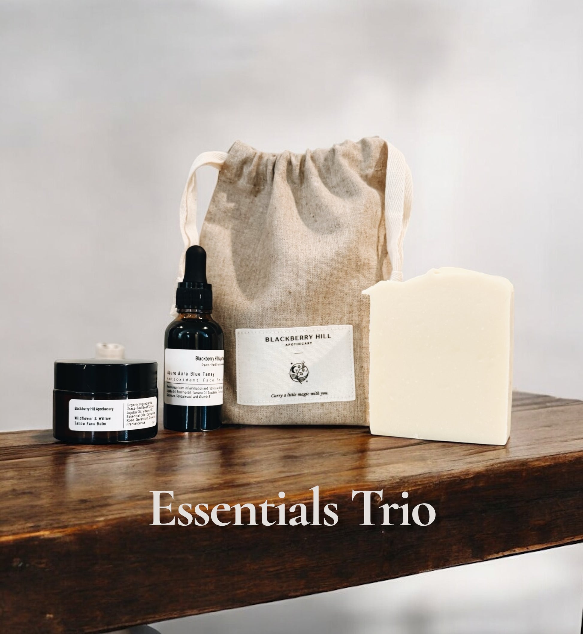 Three skincare products on a wooden surface with a drawstring bag labeled 'Blackberry Hill'.