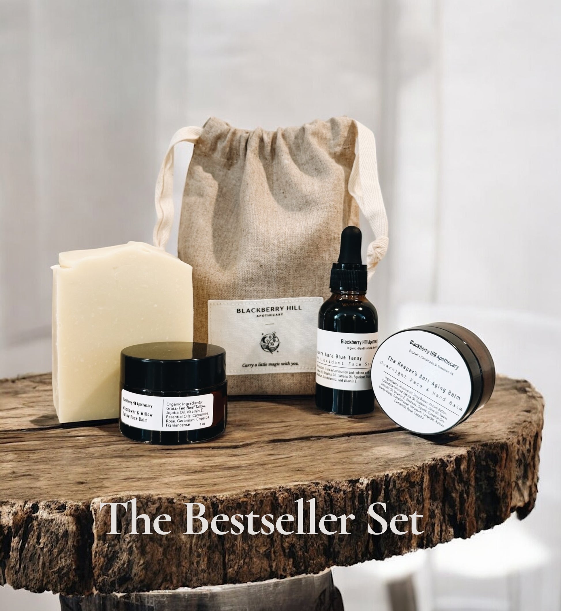 Collection of skincare products on a wooden surface with a drawstring bag labeled 'Blackberry Hill'.